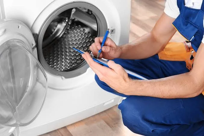 Technician recording inspection notes beside a washing machine