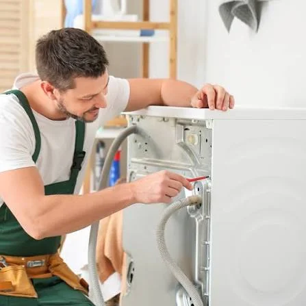 Technician checking hoses and rear connections on a washing machine